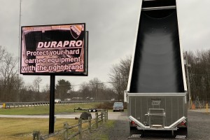 dump truck with black liner outdoors next to sign that says Durapro protect your hard earned equipment with the right brand