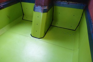 photo of a green truck bed liner with a blue border inside a truck with red sides