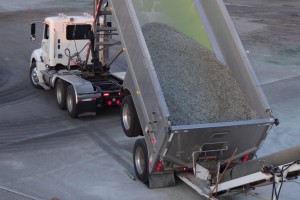 photo of a dump truck half filled with gravel and a green liner