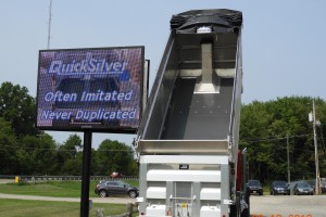 dump truck with silver liner outdoors next to sign that says Quicksilver often imitated never duplicated