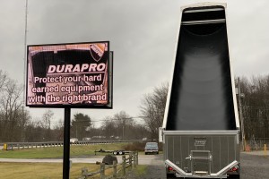 dump truck with black liner outdoors next to sign that says Durapro protect your hard earned equipment with the right brand