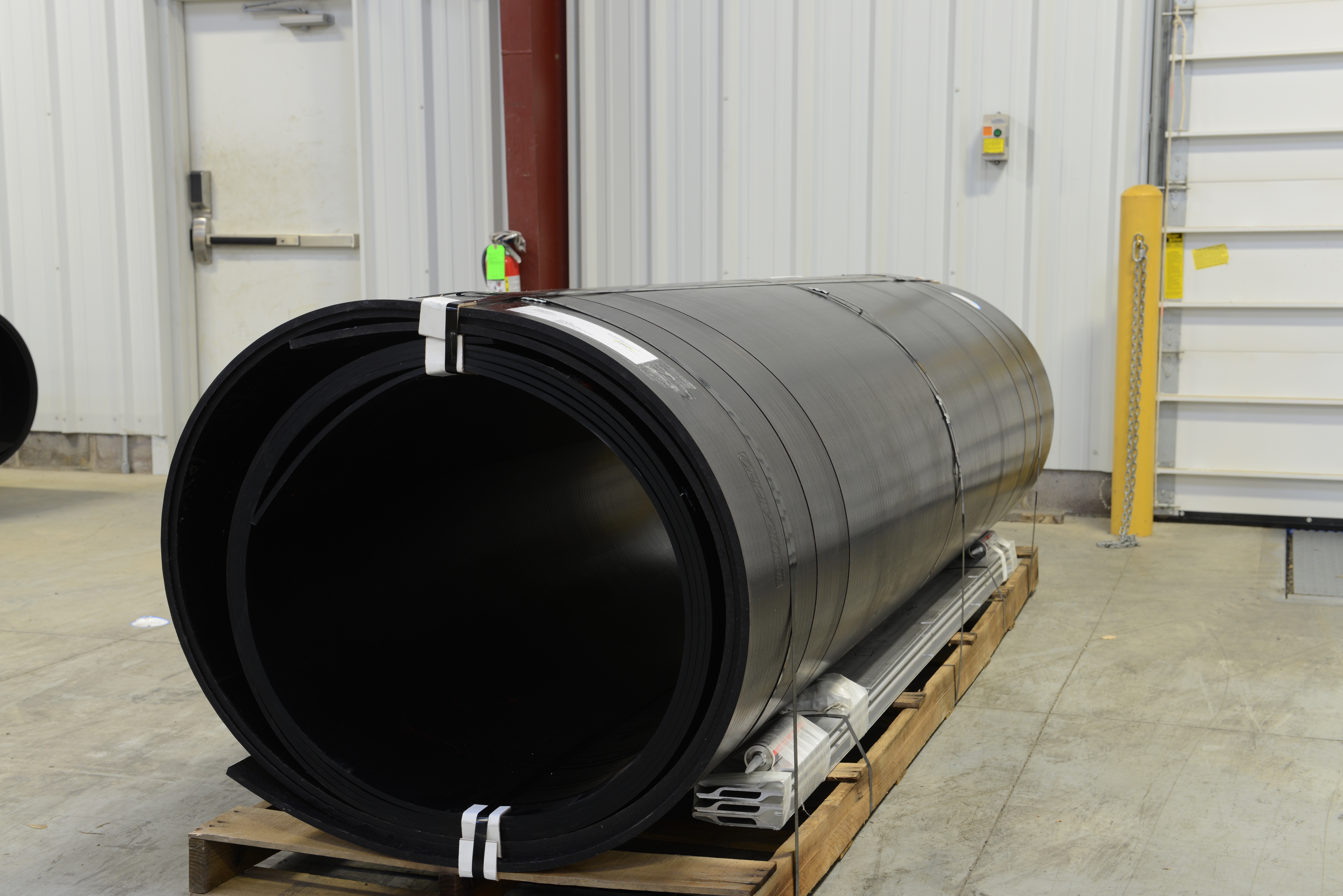 photo of a roll of black truck liner material on a pallet